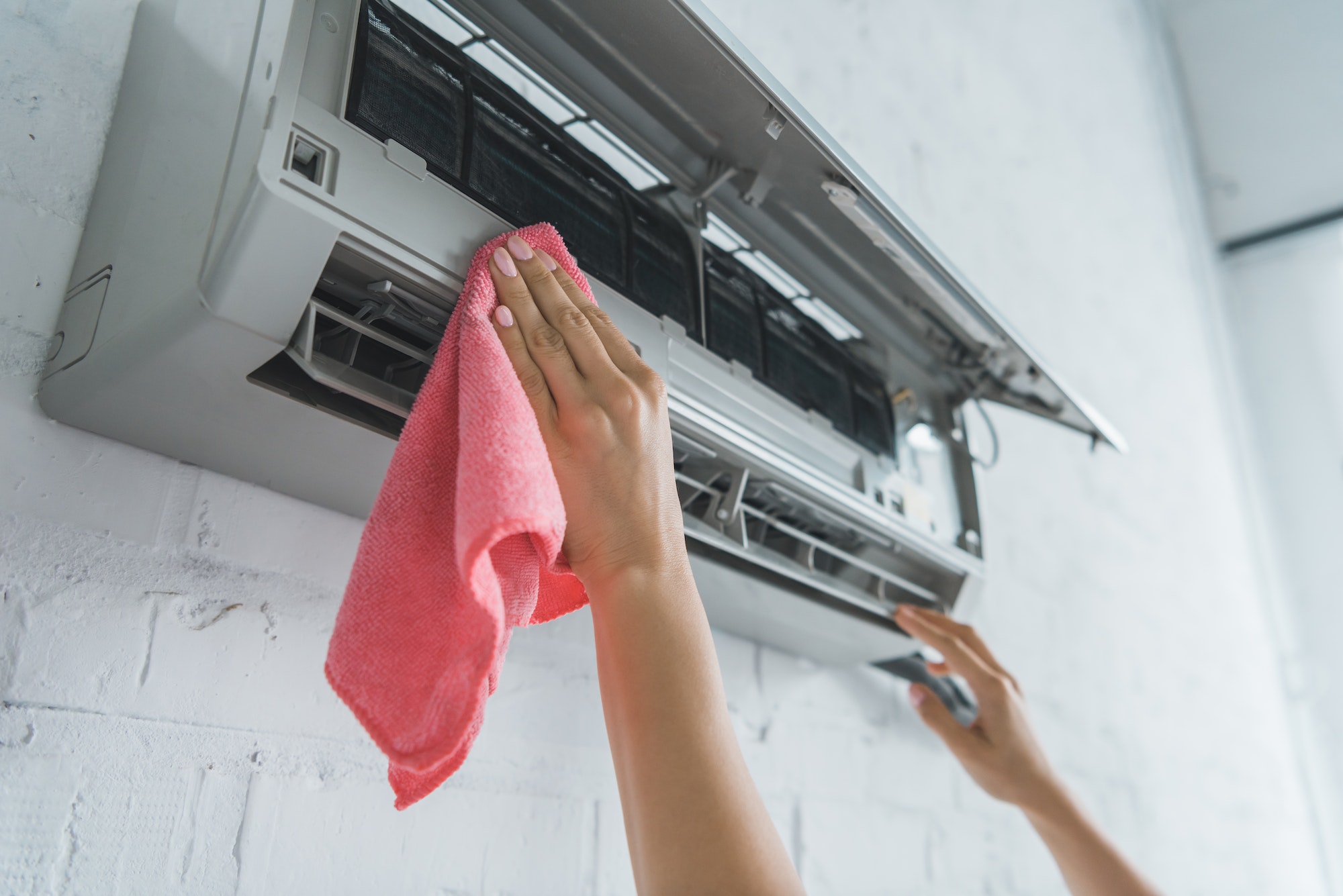 cropped view of female worker cleaning air conditioner with rag