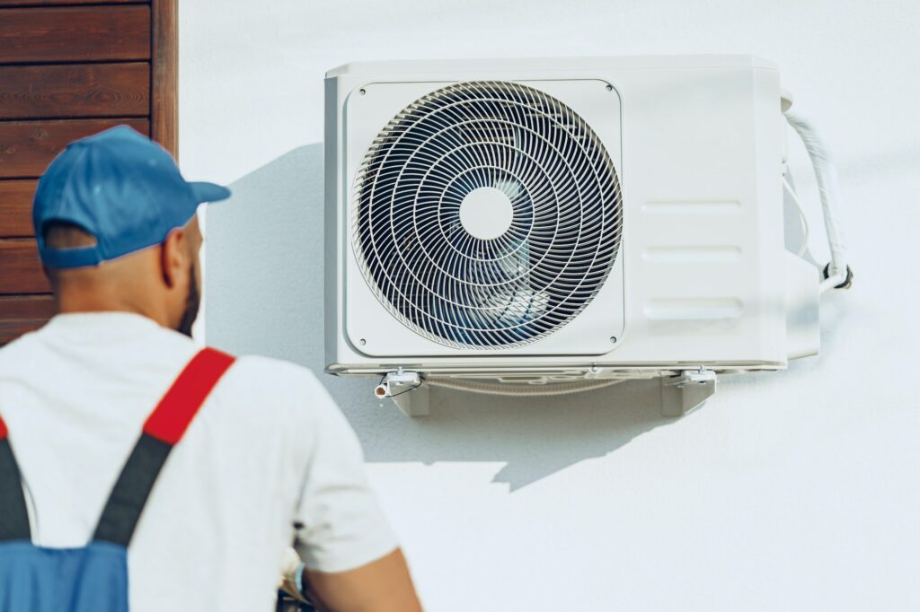Repairman in uniform installing the outside unit of air conditioner